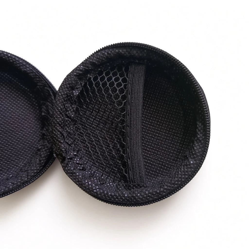 Close up view of the internal mesh compartment inside a black round hard earphone carrying case.