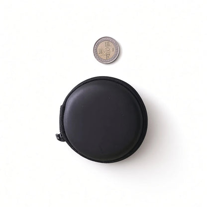 Compact black round hard shell earphone pouch next to a Sri Lankan coin showing portable mini size.