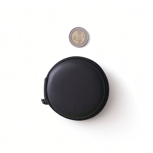 Compact black round hard shell earphone pouch next to a Sri Lankan coin showing portable mini size.